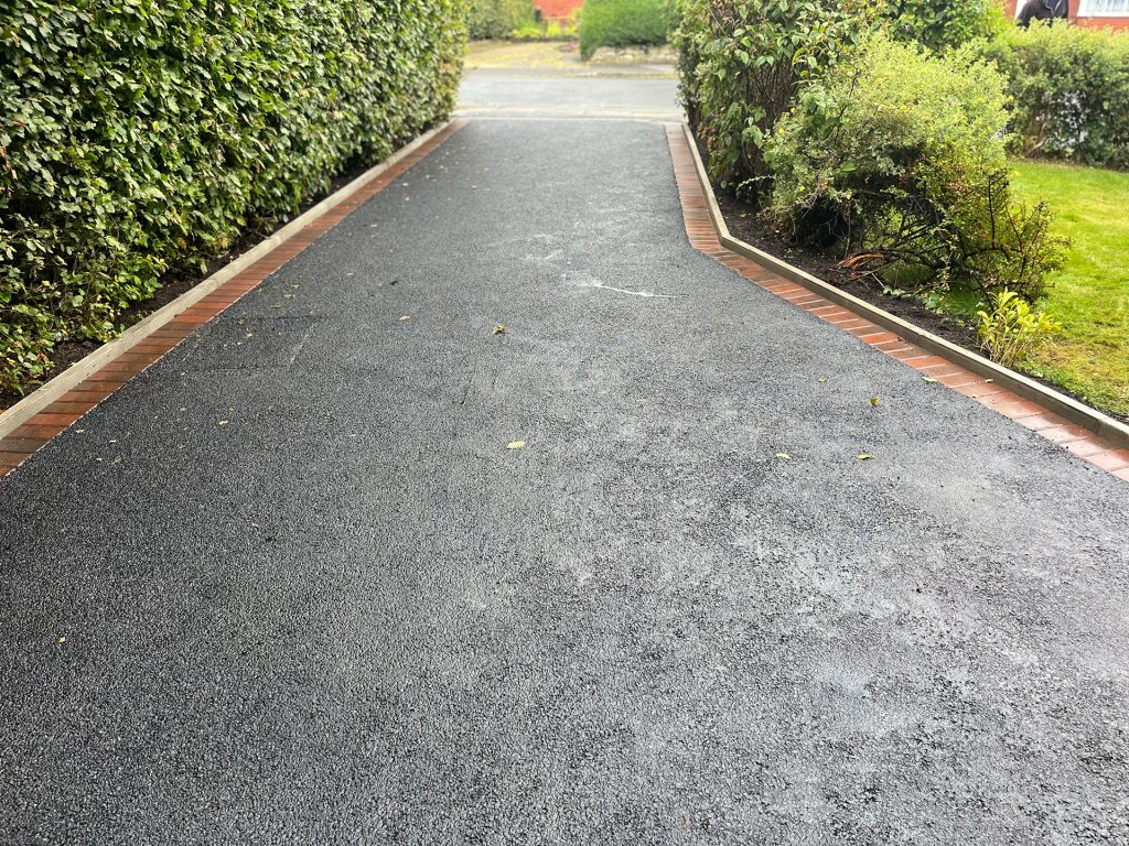 Looking down a tarmac driveway with red brick border